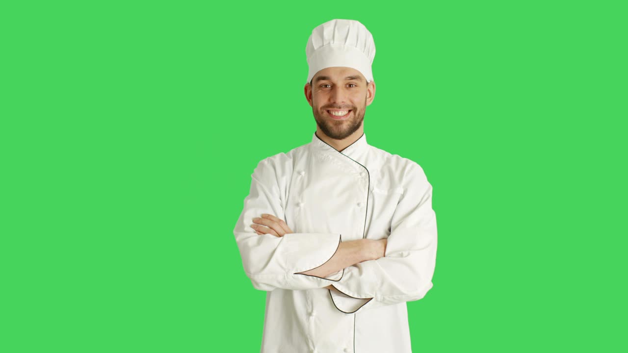 Mezzo busto di uno chef affascinante che incrocia le braccia e sorride. Lo sfondo è uno schermo verde.