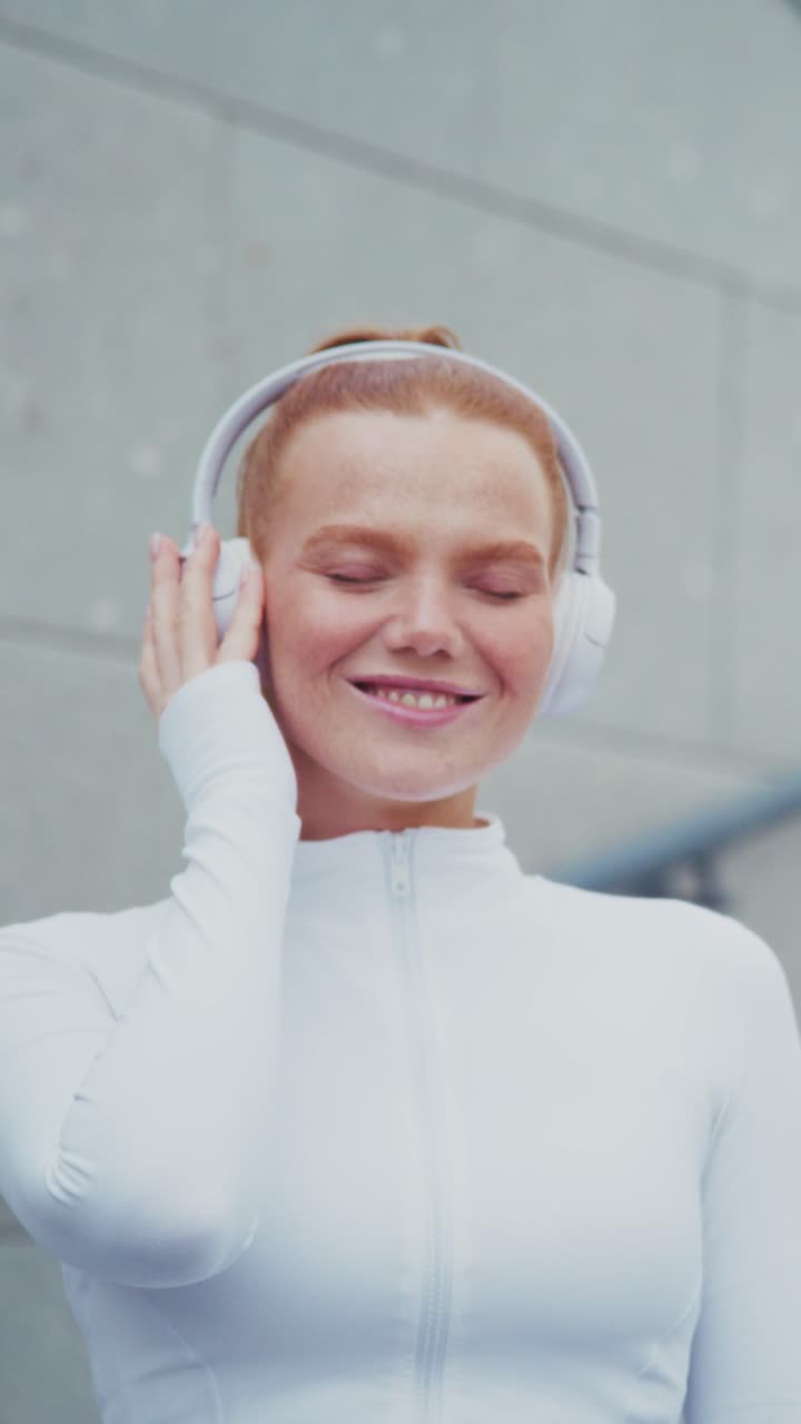 A joyful young woman with headphones savoring the music, expressing deep happiness and connection with each note in a serene urban environment