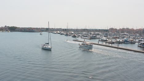 cinematic drone - aerial panorama shot of a marina with sailing boats two boat sailing in the foreground on a sunny day at zeeland at the north sea, netherlands, 25p