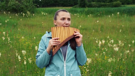 a young woman plays the pan flute in nature