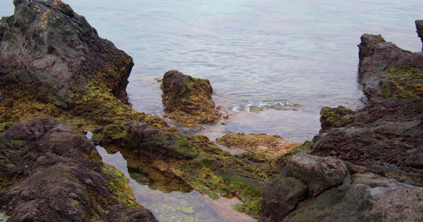 Inquadratura media delle onde che si infrangono sulla roccia vulcanica nel porto della città vecchia a Puerto del Carmen