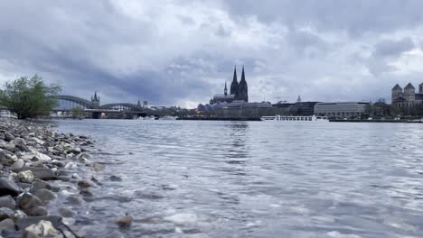 bank of the rhine with river and stones in cologne with cologne cathedral and hohenzollern bridge