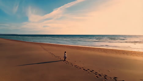 person walking on a vast sunset beach with footprints