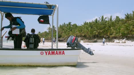 scuba divers in a boat strapping on tank after a dive in indian ocean of kenya, east africa