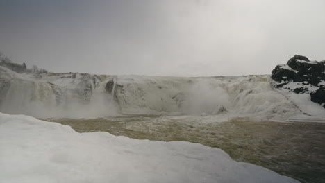 cascades from icy cliffs flowing down the cold river during winter in quebec, canada