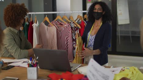 mixed race clothes designers having video call wearing face masks