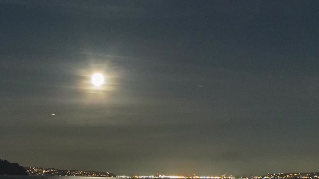 Zoom in full moon rising above shimmering waters of Puget Sound and Tacoma Washington, hyper lapse