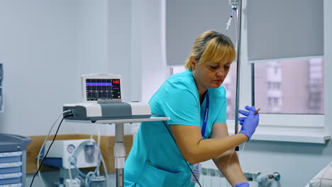 adult female nurse setting the equipment in the hospital ward. medic connects the wires from the apparatuses.