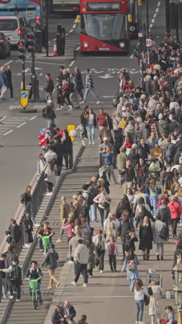 traffic and people crossing westminster bridge next to the houses of parliament, london, uk in vertical