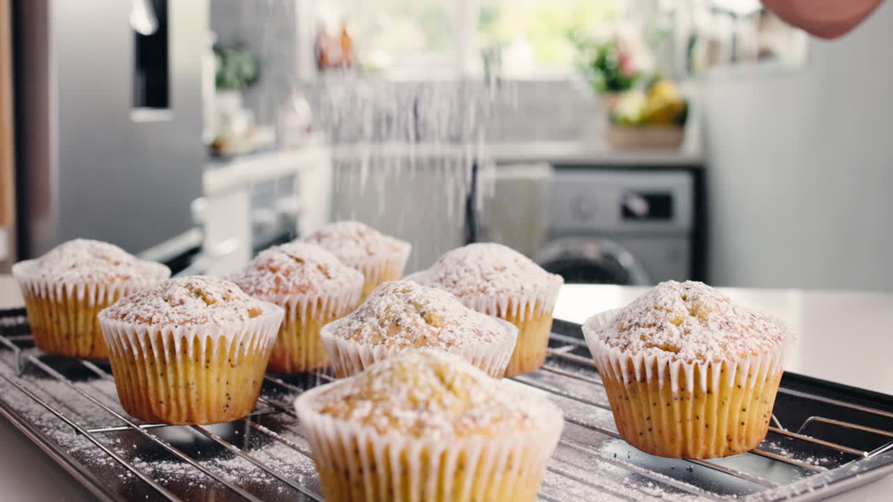 Cosparsi di zucchero a velo dei muffin appena sfornati in una cucina moderna