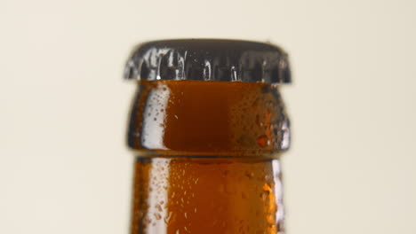 Macro-close-up-shot-of-a-slow-rotating-wet,-brownisch-beer-bottleneck