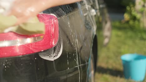 doing circles with water, foam, soap and a sponge over the body of sedan car