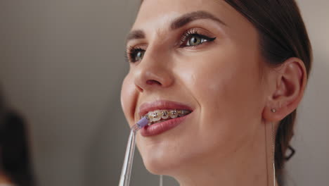 woman with braces using a waterpik for teeth cleaning