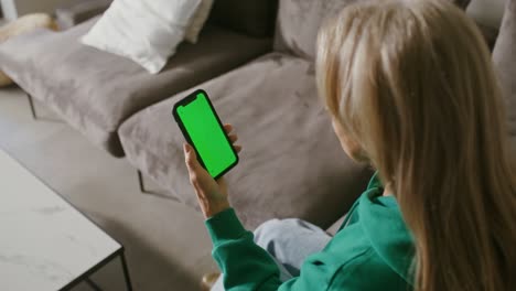 an elderly woman looks at the screen of a mobile phone she is holding