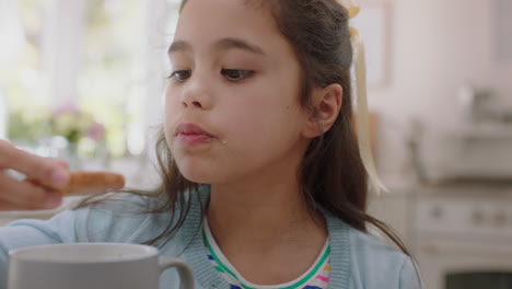 niña feliz comiendo galletas sumergiendo galletas en chocolate caliente disfrutando de una deliciosa golosina en casa en la cocina