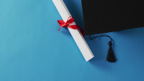 Video-of-graduation-hat-and-diploma-on-blue-background