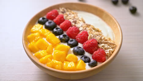 homemade yogurt bowl with raspberry, blueberry, mango and granola - healthy food style