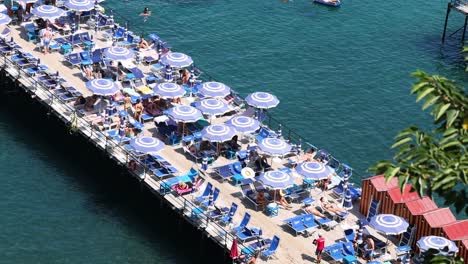 crowded beach pier with umbrellas and sunbathers