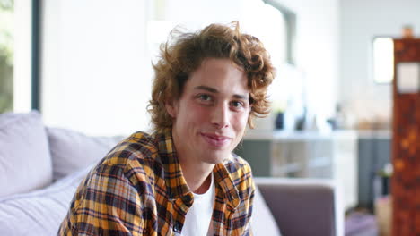 Portrait-of-happy-caucasian-man-sitting-on-sofa-at-home,-slow-motion