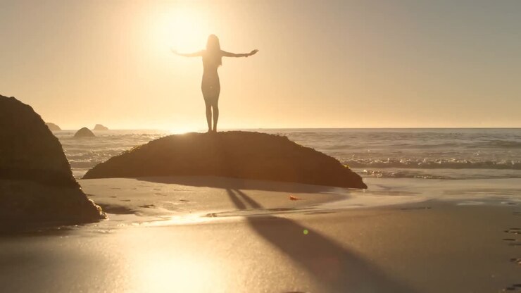 Silhueta de uma mulher de braços abertos na praia