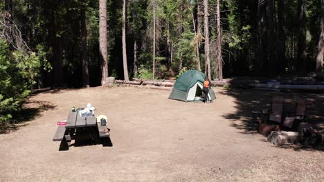 low aerial dolly shot towards camper exiting tent in campsite