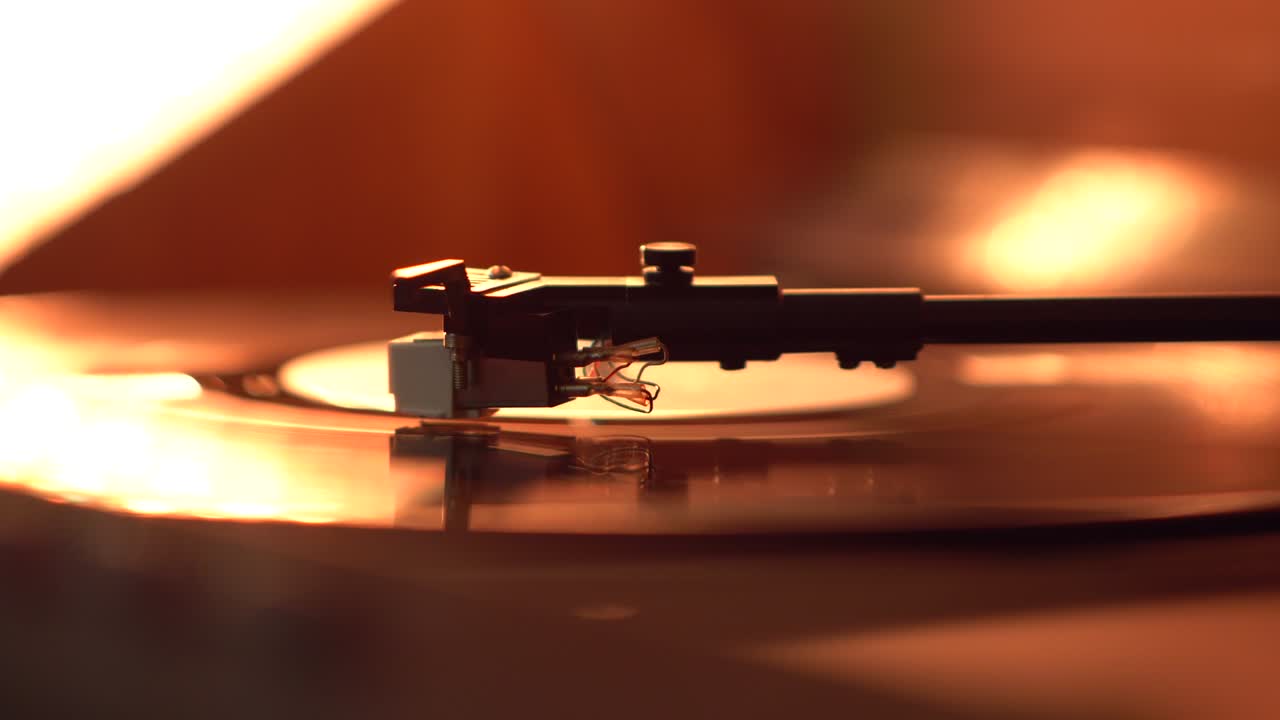 톤 팔과 회전하는 비닐 레코드가 따뜻한 빛으로 조명됩니다.