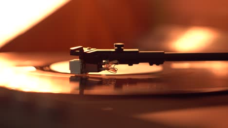 cerca de un brazo de tono y un disco de vinilo giratorio iluminado con luz cálida.