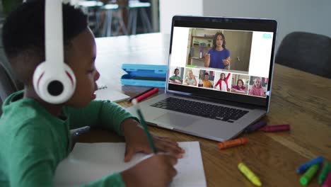 Colegial-Usando-Una-Computadora-Portátil-Para-Clases-En-Línea-En-Casa,-Con-Diversos-Maestros-Y-Clases-En-La-Pantalla