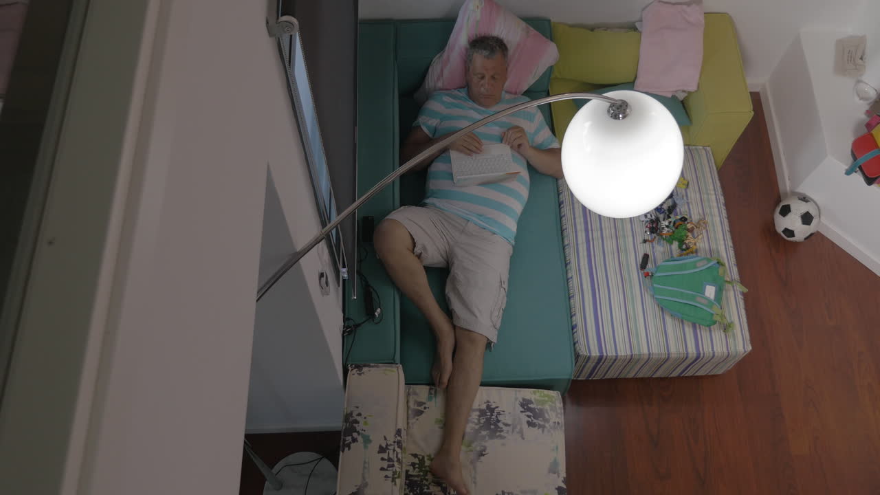 человек лежит на диване и просматривает интернет на ноутбуке