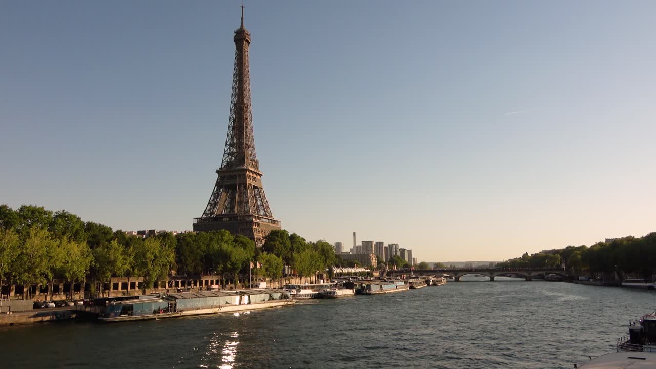Vista panoramica ad angolo elevato che mostra la Torre Eiffel accanto alla Senna con lo skyline della città di Parigi, barche, ponti e la calda luce del crepuscolo. Scenica vista urbana di riferimento per viaggi e turismo.