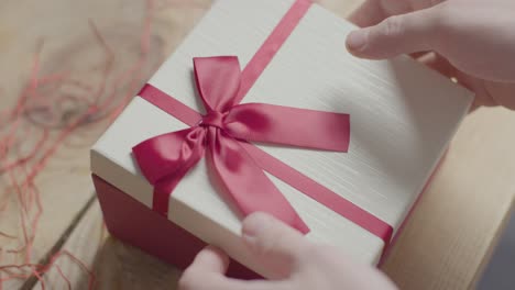 close up shot of man gift wrapping romantic valentines present of perfume in box on table