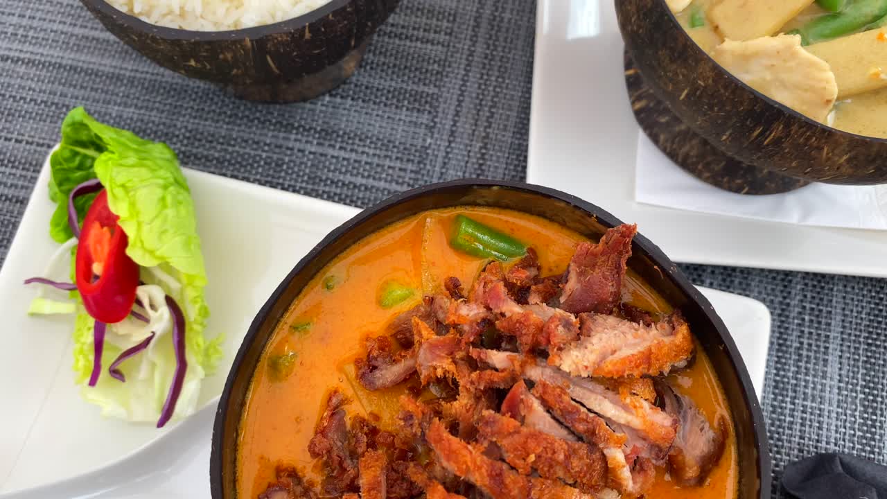 plato tradicional tailandés de pato crujiente de curry rojo y pollo de curry verde con arroz en un cuenco de coco, restaurante de cocina tailandesa, tiro de 4k