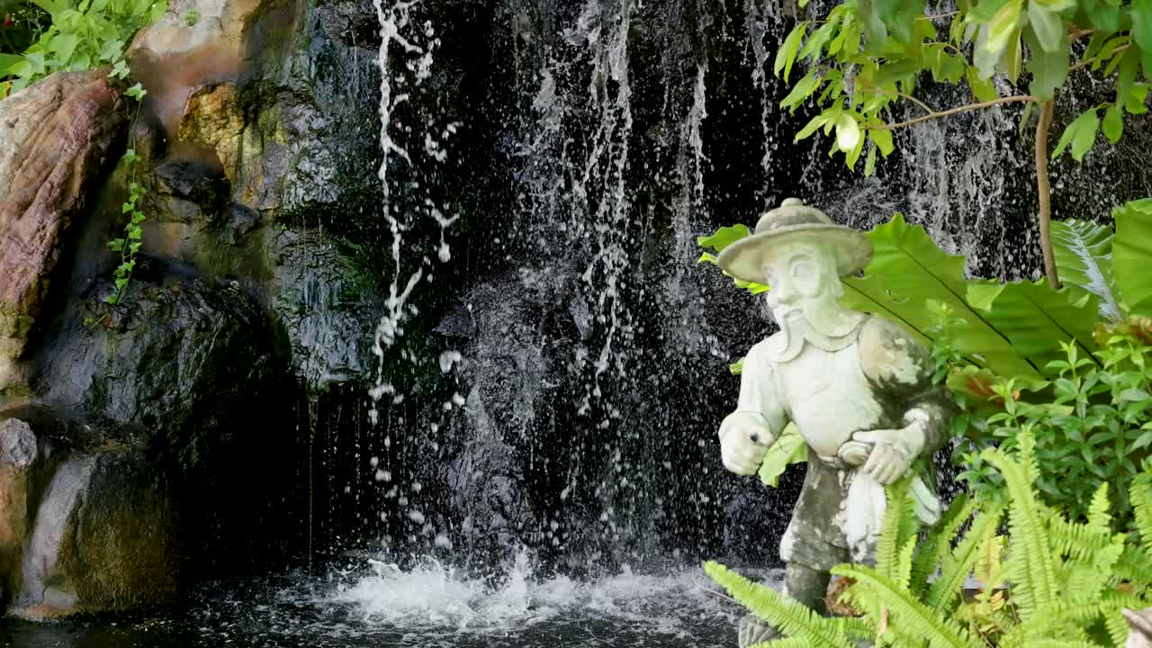 une cascade paisible avec une statue dans un jardin de temple luxuriant