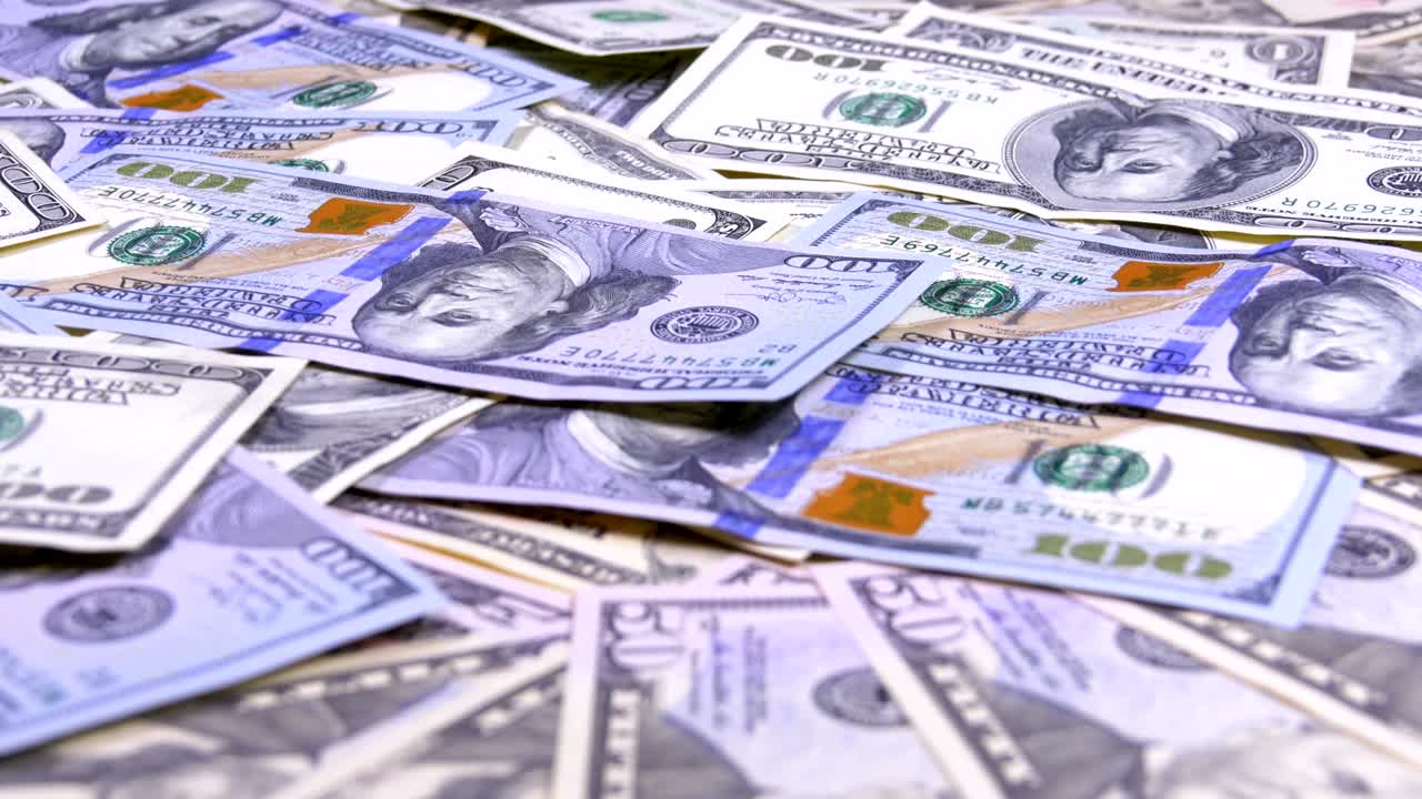 billetes de dólares estadounidenses de diferentes denominaciones girando en la mesa