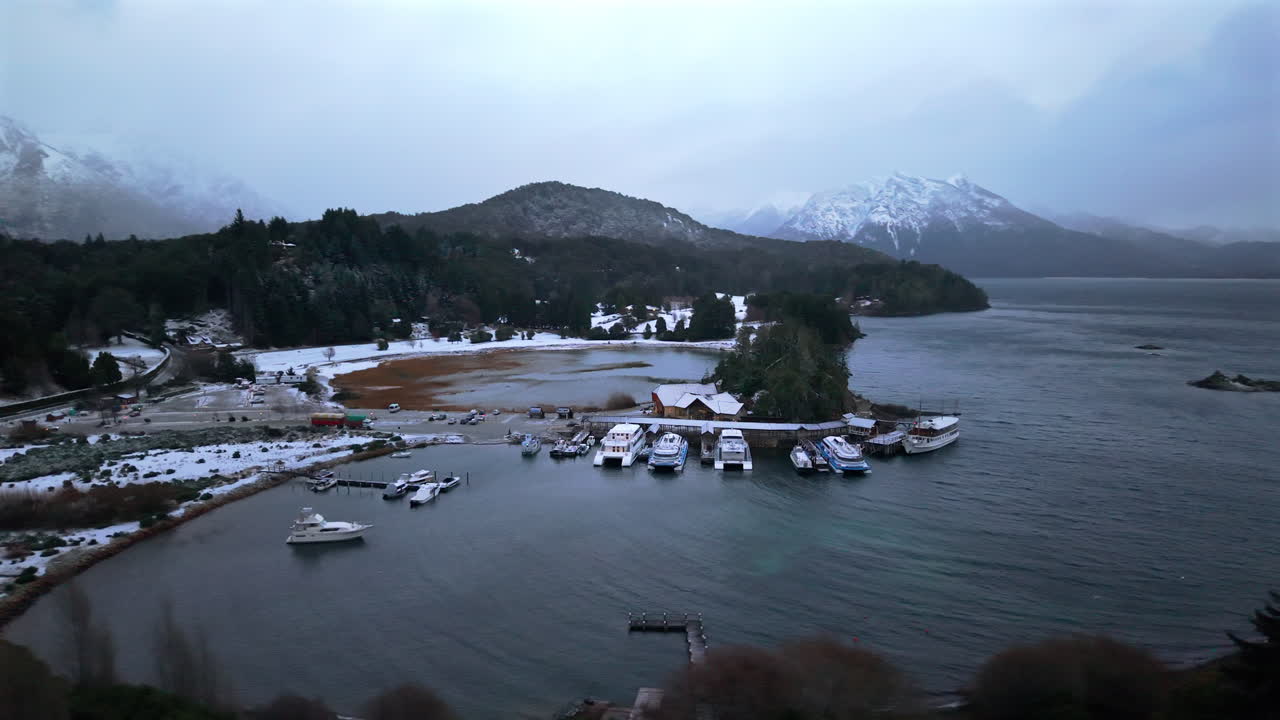 Mid-altitude shot captures yachts straining against choppy waves among fog and rain, with the Andes looming. Ideal for stormy weather or adventure documentaries