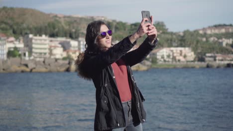 wide shot of a girl taking selfie and pictures with sea in the background in slow motion