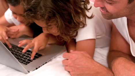 family using laptop on bed