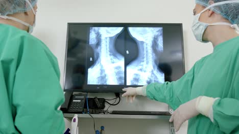 Diversos-Cirujanos-Usando-Batas-Quirúrgicas-Mirando-Exploraciones-De-Rayos-X-En-Quirófano,-Cámara-Lenta