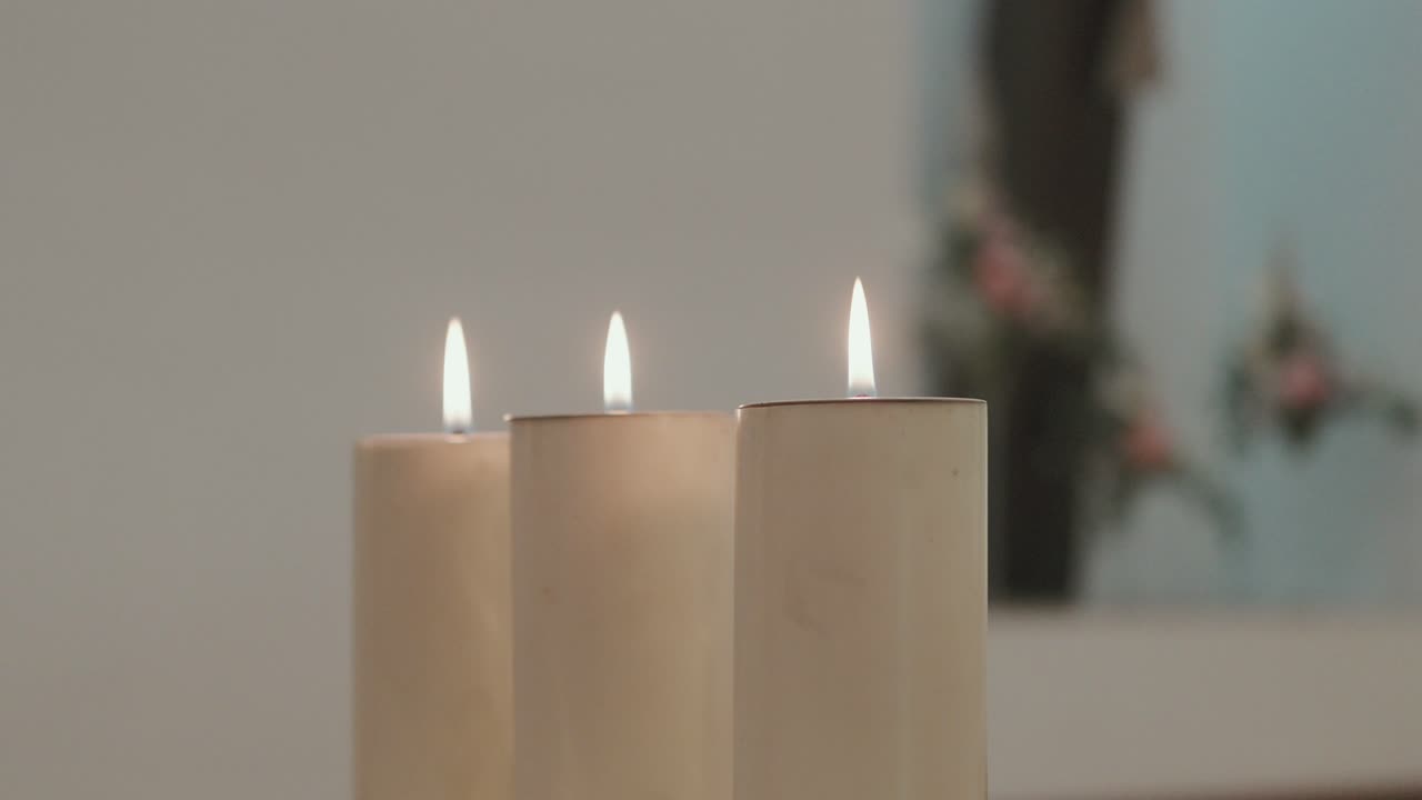 Close up of three softly glowing candles symbolizing calmness, reflection, and light