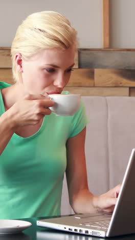 pretty blonde using her laptop and drinking coffee