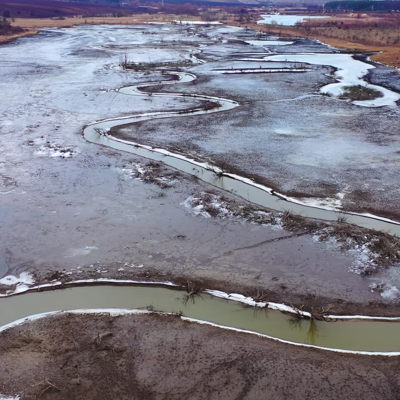 Tortuous river in muddy place. Ecological problems with water. Global warming. Narrow stream from dried river. Nature in danger. View from above