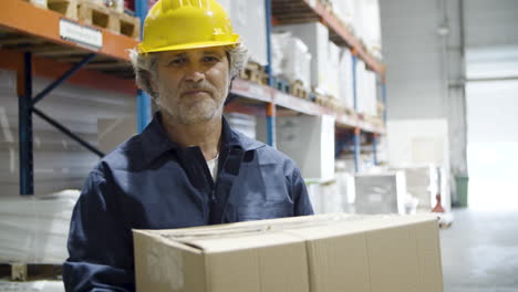 caucasian male worker holding cardboard box and looking at the camera