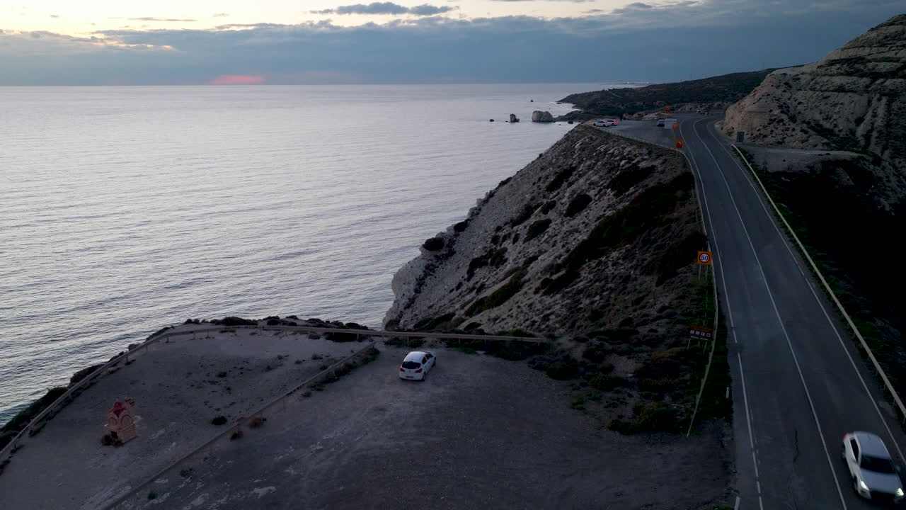 파포스 에 있는 아프로디테스 바위 근처 의 해안 도로 의 황혼 에 있는 공중 풍경, 주차 된 차 와 지평선 으로 어 있는 조용 한 바다