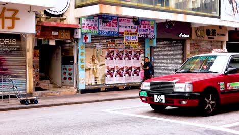 a red taxi drives past colorful storefronts