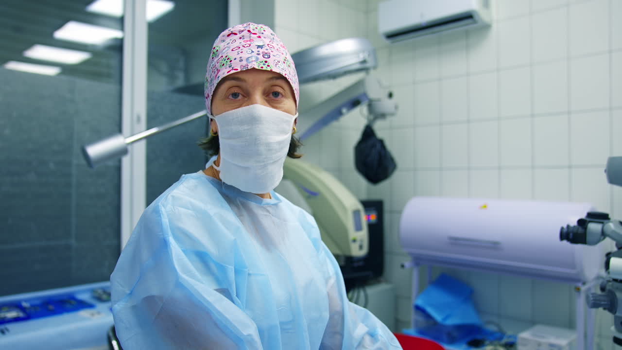 Doctor in scrubs and facial mask tells methods of vision correction to the camera. Modern clinic background.