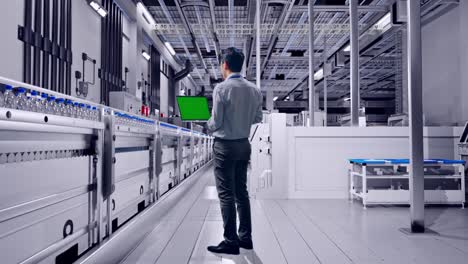 full body back view of an asian male professional worker standing with water production in bottling factory, typing on laptop's keyboard with green screen and look at the factory once