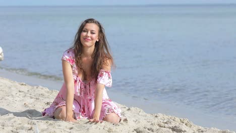 una hermosa modelo en la playa lanzando arena juguetonamente hacia el espectador