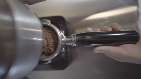 a reveal shot of a coffee grinder processing coffee beans and collected in a portafilter