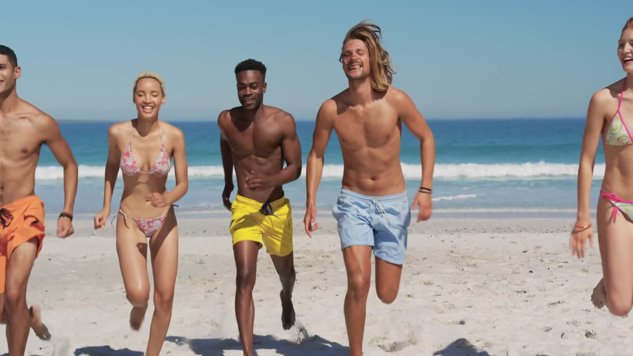 Amici giovani che corrono in spiaggia 4k