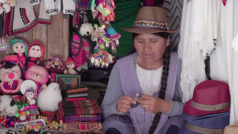 medium shot of traditional woman (cholita) weaving in the recoleta market, sucre